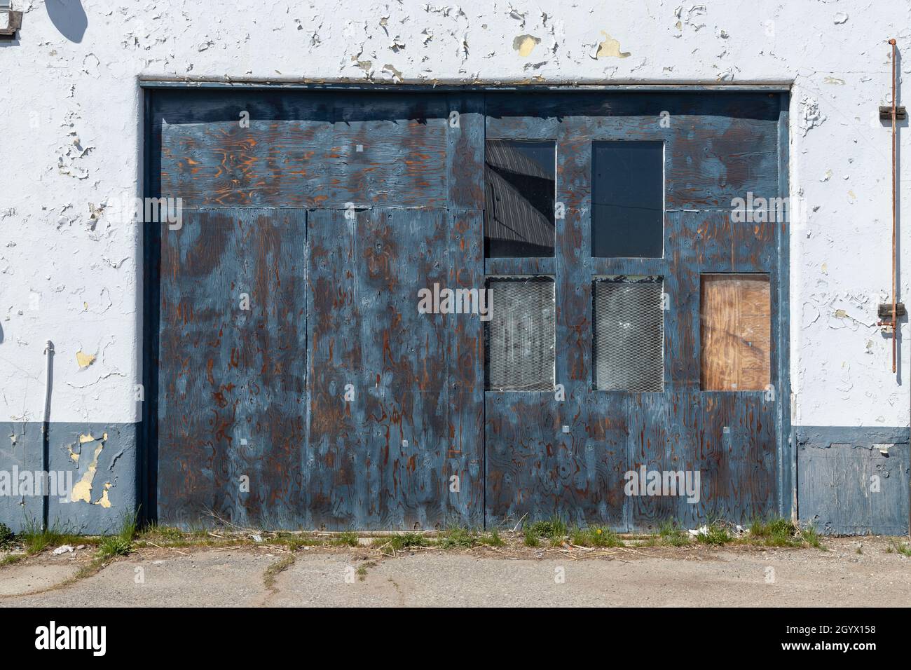 Porte bleue avec fenêtres sur le vieux mur grungy avec peinture de pealing bonne pour l'arrière-plan Banque D'Images