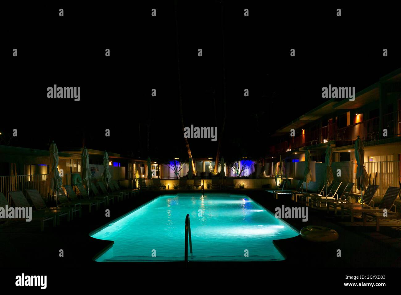 Piscine dans un hôtel avec parasols pliés et chaises de plage la nuit Banque D'Images