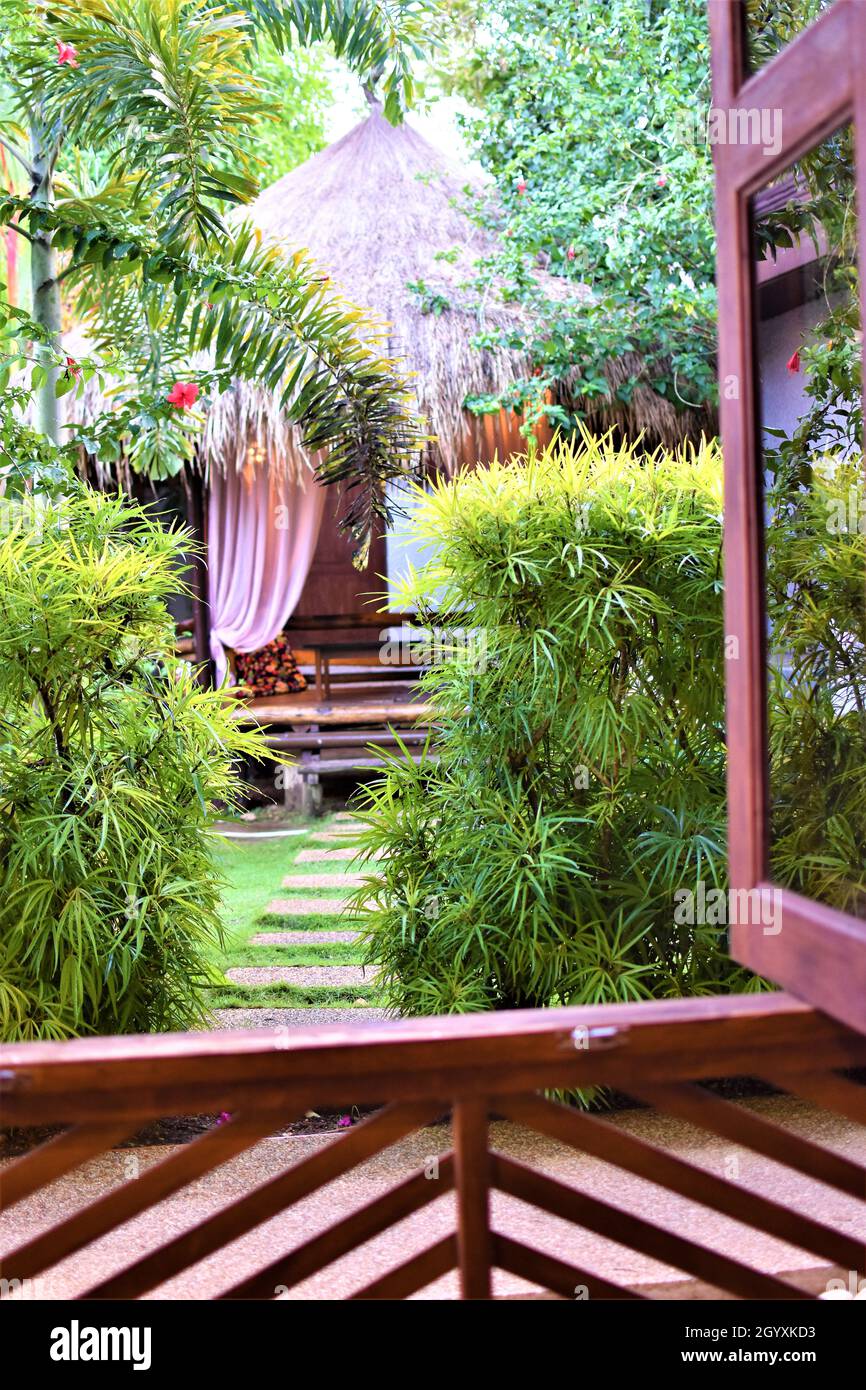 Cabine de jardin en bambou et chaume de palmier, entourée de plantes et d'arbres Banque D'Images