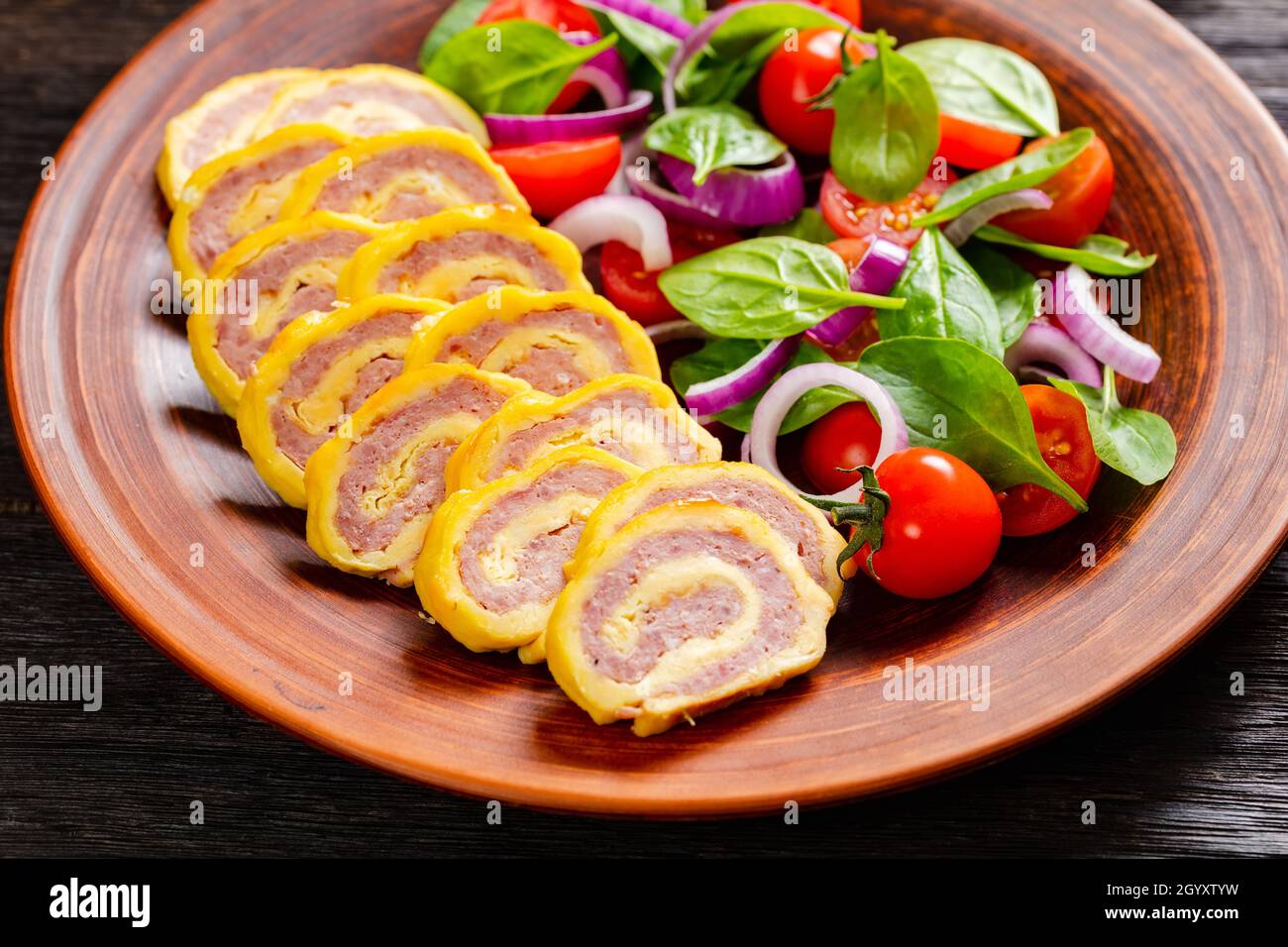 petit-déjeuner au jambon et au fromage hachés, omelettes et salade d'oignons rouges aux épinards frais sur une assiette rustique sur une table en bois, vue horizontale depuis un Banque D'Images