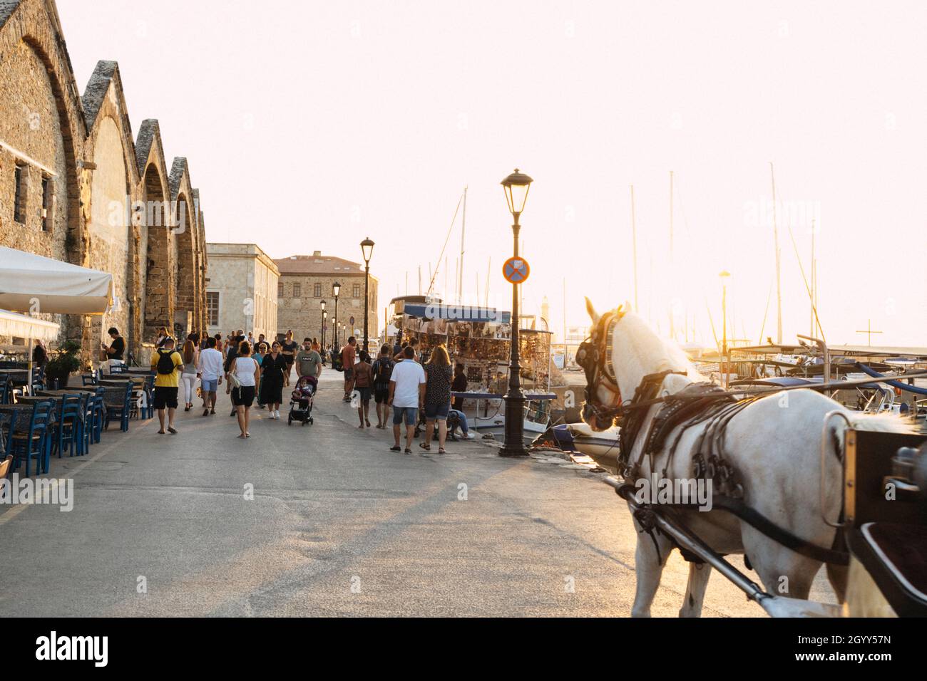 Touristes marchant sur la promenade du front de mer dans la vieille ville de Chania au coucher du soleil, île de Crète, Grèce Banque D'Images