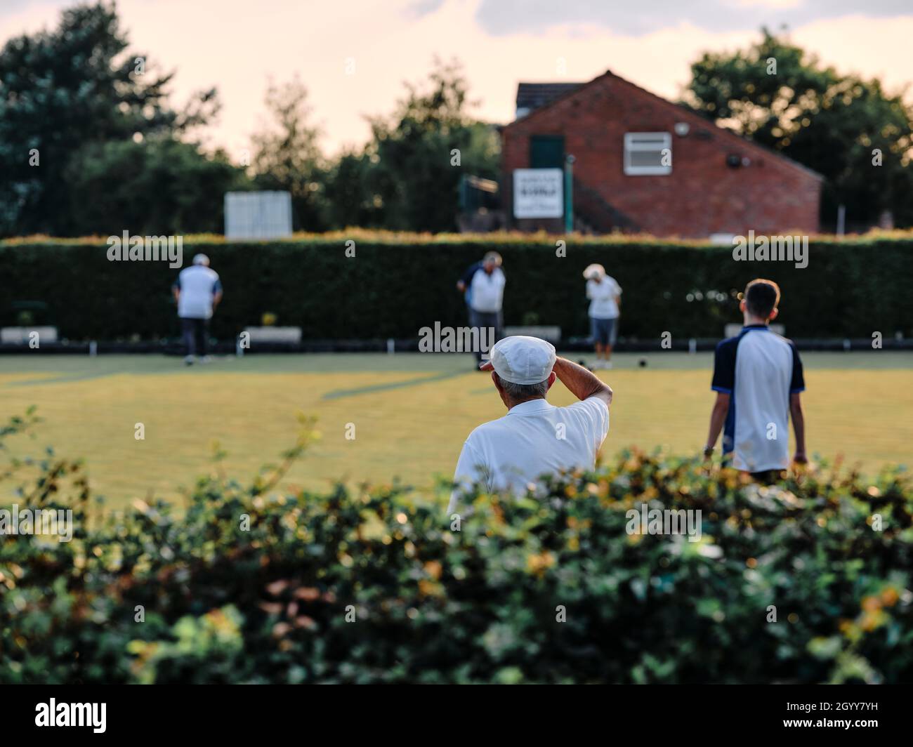 Joueurs de boules de pelouse / joueurs de boules en blanc lors d'un match de tournoi de soirée d'été dans les zones rurales Angleterre Royaume-Uni - British Summer Bowling Green club Banque D'Images