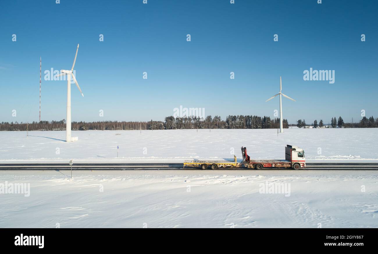 Remorque de camion vide se déplaçant sur une route enneigée d'hiver vue aérienne de drone Banque D'Images Remorque de camion vide se déplaçant sur une route enneigée d'hiver vue aérienne de drone Banque D'Images
