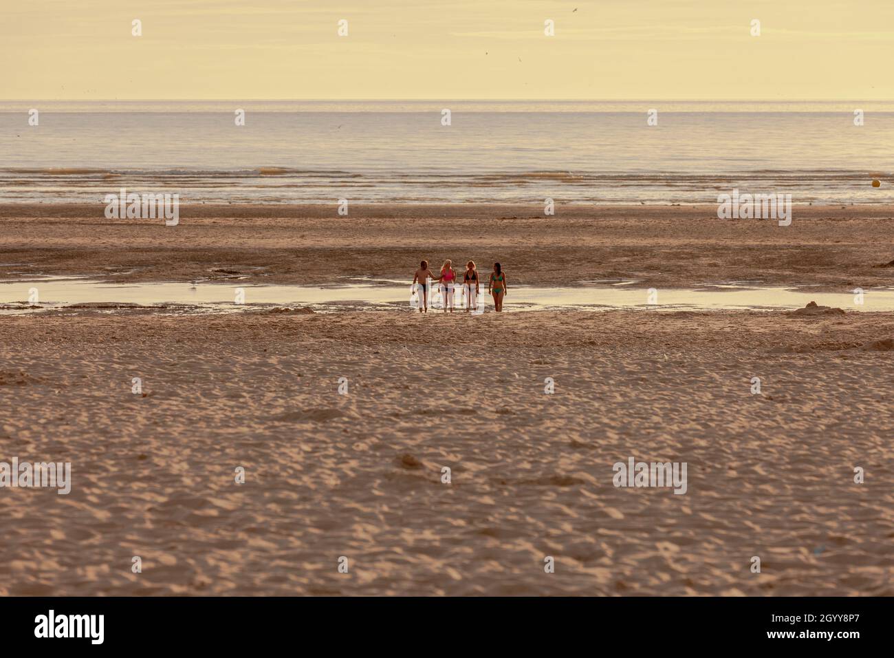Quatre personnes sur la plage au coucher du soleil Banque D'Images