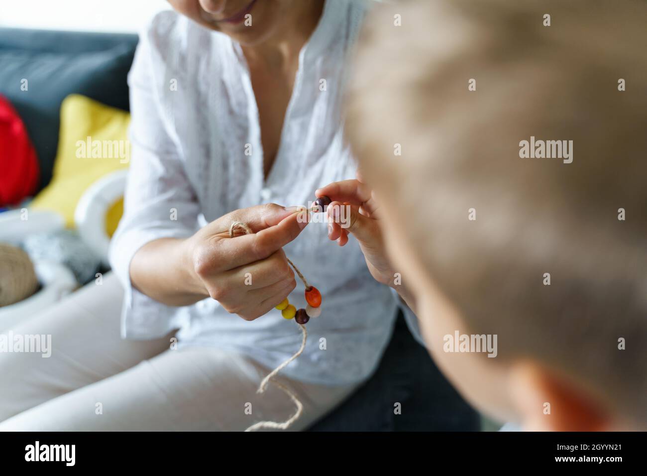 Vue de dessus sur la section médiane d'une femme inconnue tenue corde avec perles en bois ou en plastique faire des matériaux nature bracelet collier à la maison - Creative des Banque D'Images