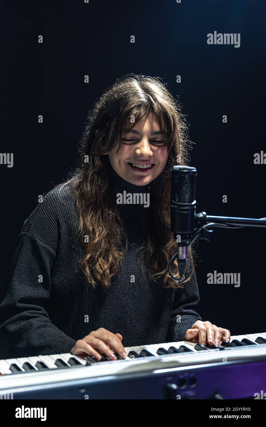 Fille gaie dans le processus d'enregistrement de contenu musical dans le studio, l'enregistrement de la voix dans un microphone professionnel, le concept d'apprentissage du piano Banque D'Images