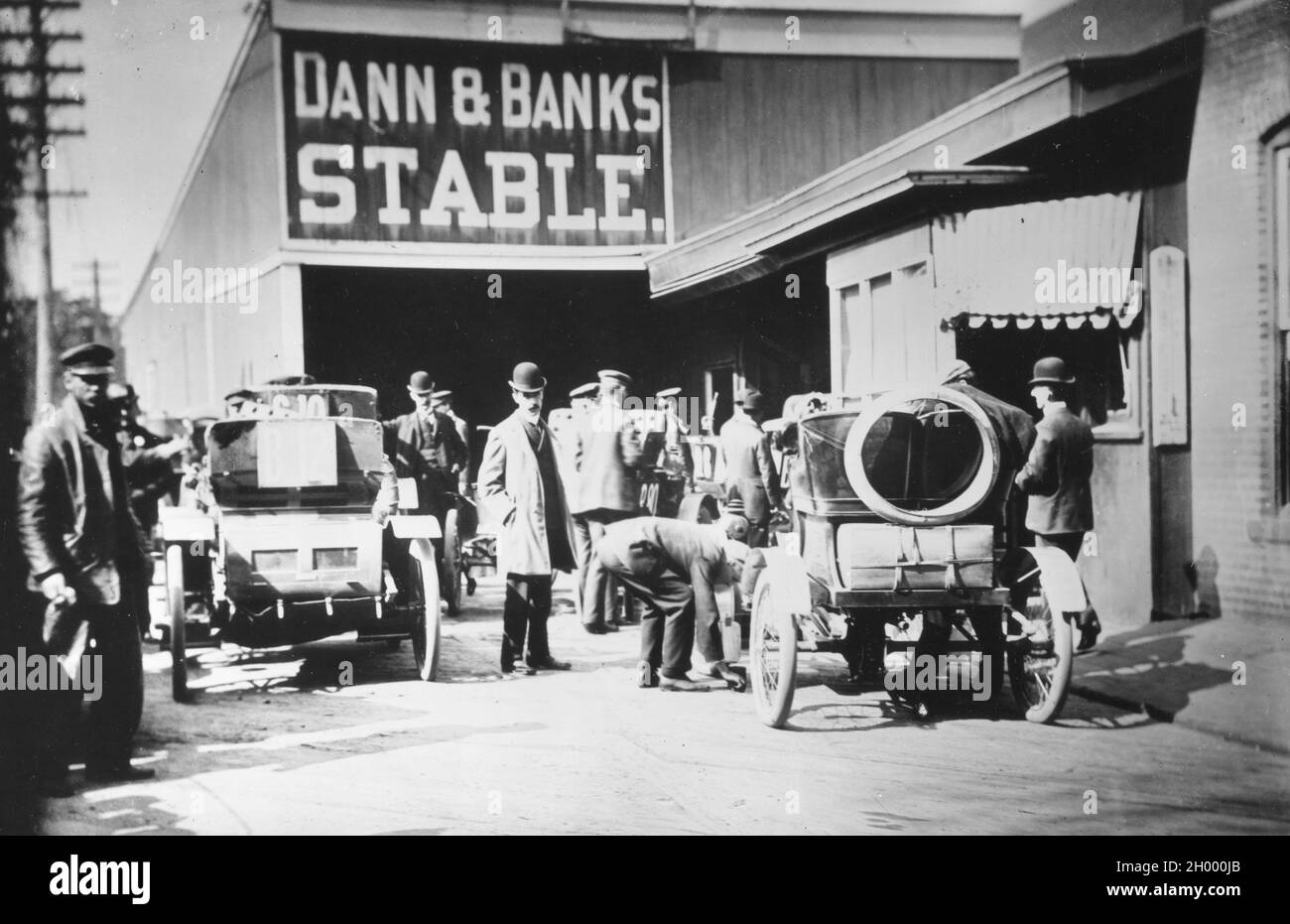 Les jeunes automobilistes achètent de l'essence pour leurs automobiles à une livery stable avant 1912. Banque D'Images