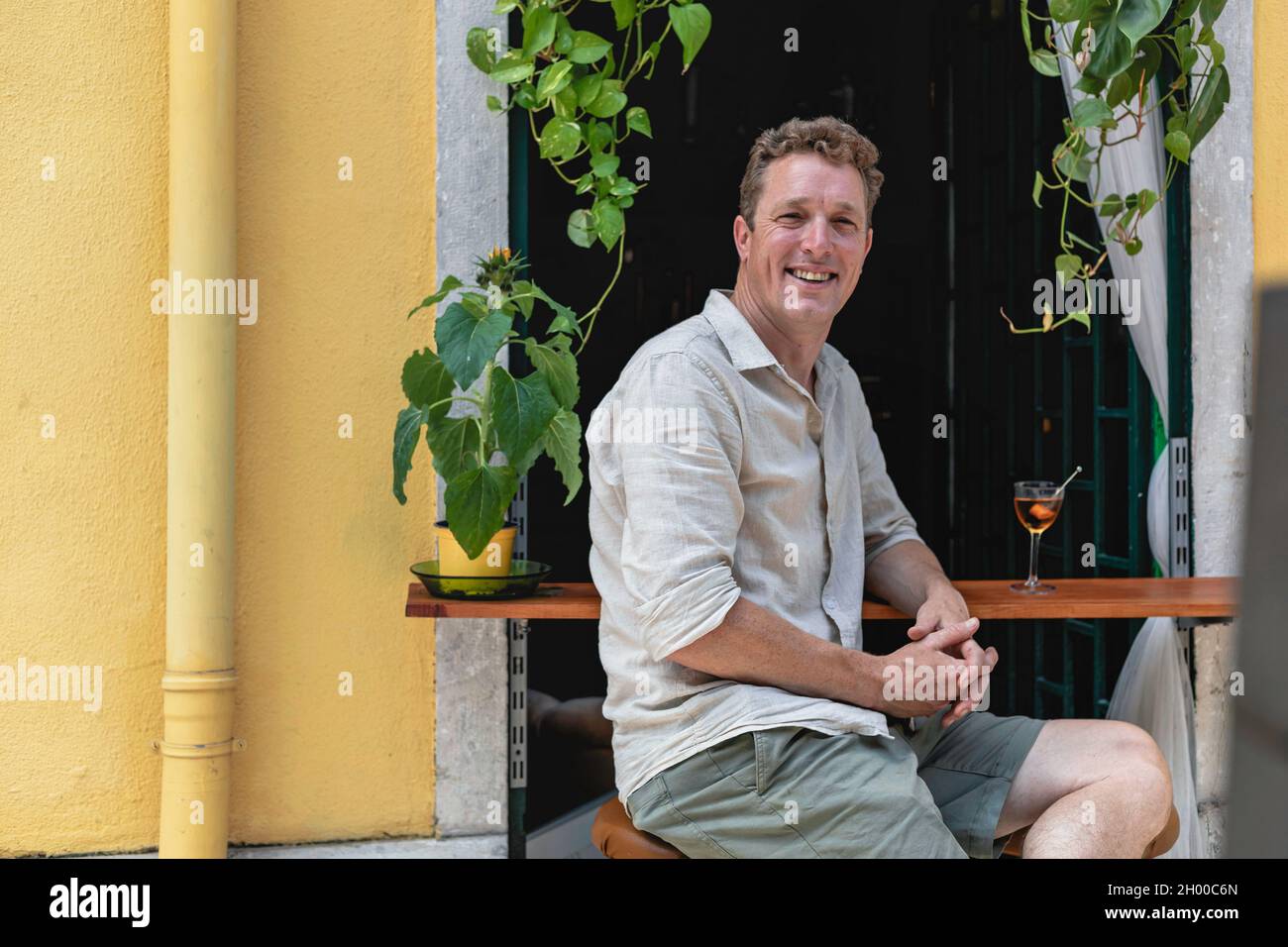 Un homme joyeux se détendant devant un bar à cocktails avec de l'herbe  verte sur la fenêtre et de boire un verre, Lisbonne, Portugal Photo Stock -  Alamy