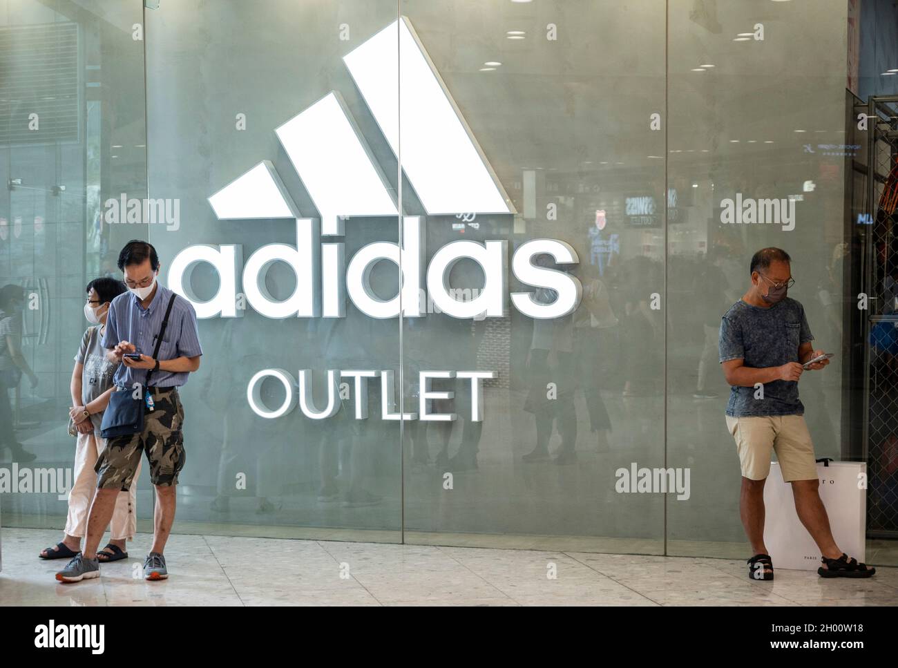 Hong Kong, Chine.07e octobre 2021.Les acheteurs se tiennent à l'extérieur de la marque allemande de vêtements de sport multinationaux Adidas Outlet Store et logo à Hong Kong.Crédit : SOPA Images Limited/Alamy Live News Banque D'Images