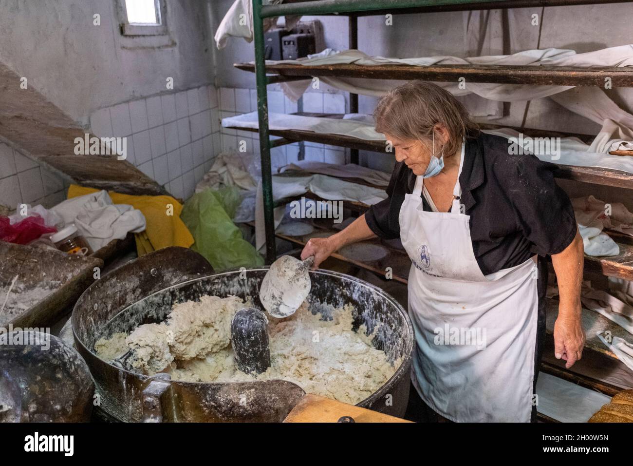 Une femme mélange la pâte dans une boulangerie traditionnelle du village chypriote, village d'Arsos, Chypre. Banque D'Images