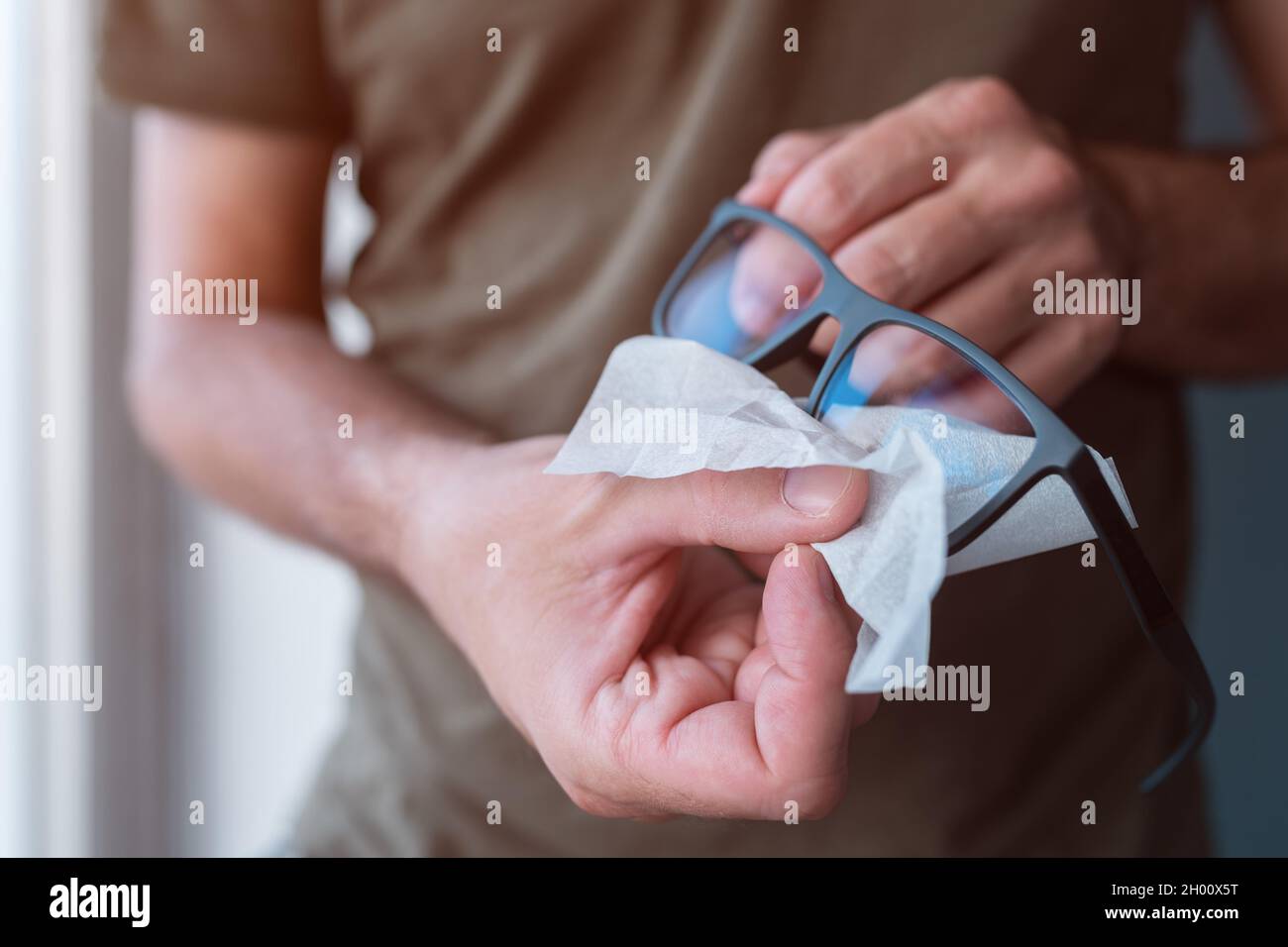 Homme nettoyant lunettes, gros plan des mains avec mise au point sélective Banque D'Images
