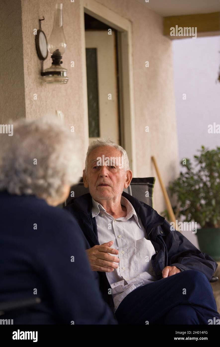 Homme et femme senior assis sur la terrasse et parlant au printemps Banque D'Images