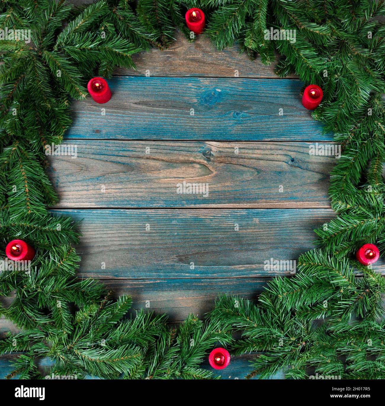 Vue en hauteur d'une couronne complète et de bougies rouges dans la bordure circulaire sur des planches de bois vieillies bleues pour les vacances d'hiver de Noël ou N Banque D'Images