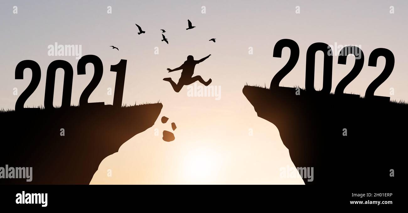 Un jeune homme saute entre 2021 et 2022 ans avec des oiseaux volants sur fond de ciel.Ciel coloré en soirée.Photo du concept de la nouvelle année Banque D'Images