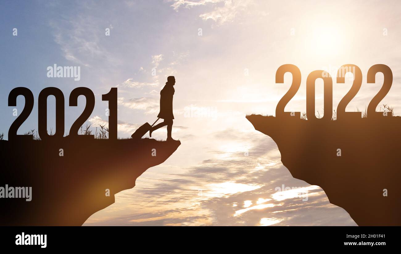 Nouvelle année 2022 est à venir.Homme avec bagages va de 2021 à 2022 ans.Arrière-plan de la montagne et du coucher du soleil, du ciel et des nuages.Concept de planification et Banque D'Images