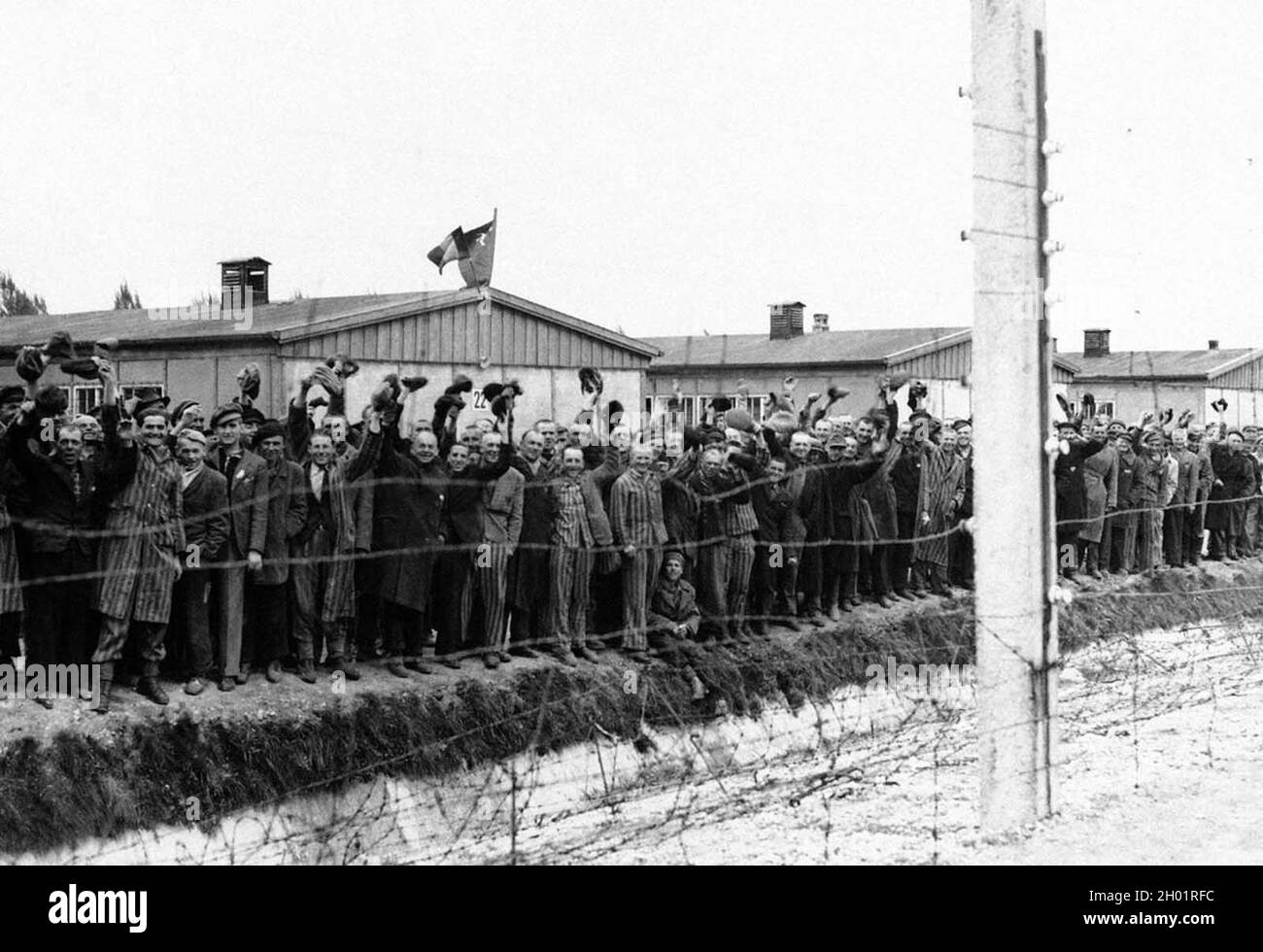 Les prisonniers de Dachau à la clôture électrique applaudissent les soldats américains à la fin de la guerre, Banque D'Images