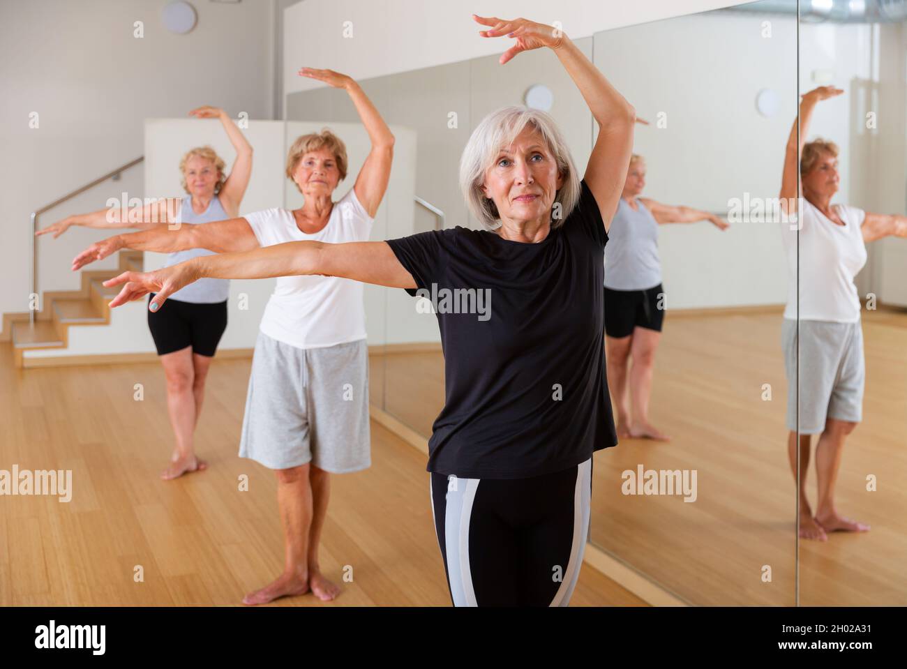 Femme mature pratiquant des mouvements de danse classiques pendant le cours de groupe Banque D'Images
