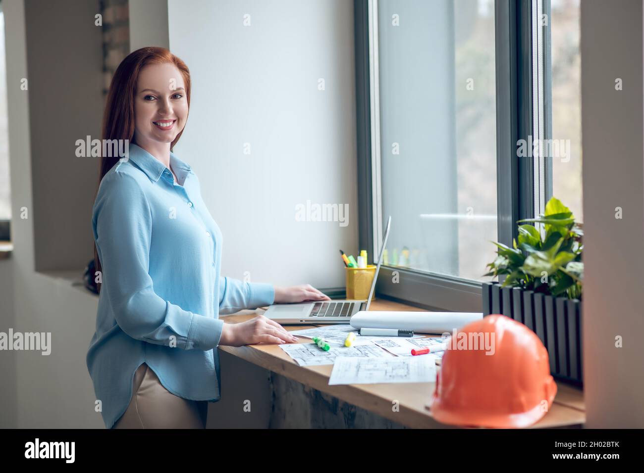 Femme souriante travaillant avec des schémas sur le rebord de la fenêtre Banque D'Images