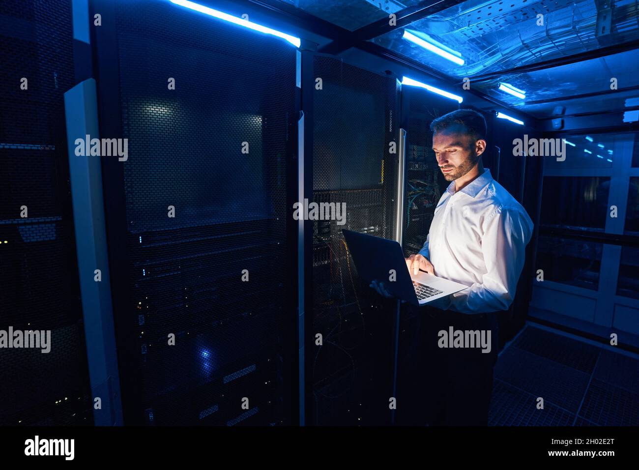 Administrateur système professionnel en cliquant sur l'ordinateur portable à proximité des armoires serveur Banque D'Images