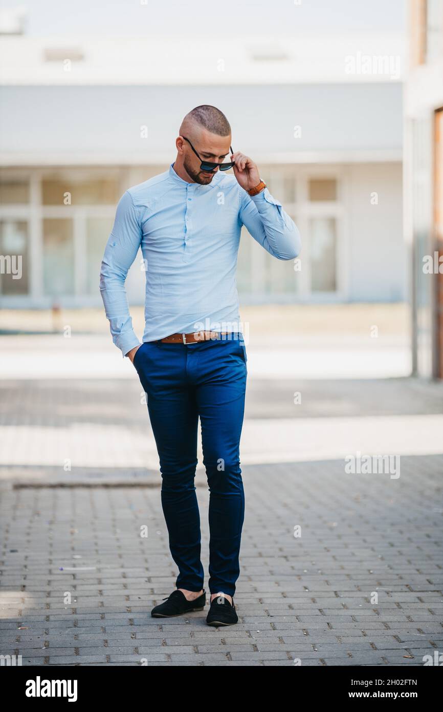 Cool beau homme caucasien portant une chemise bleu clair et des lunettes de  soleil posant à l'extérieur Photo Stock - Alamy