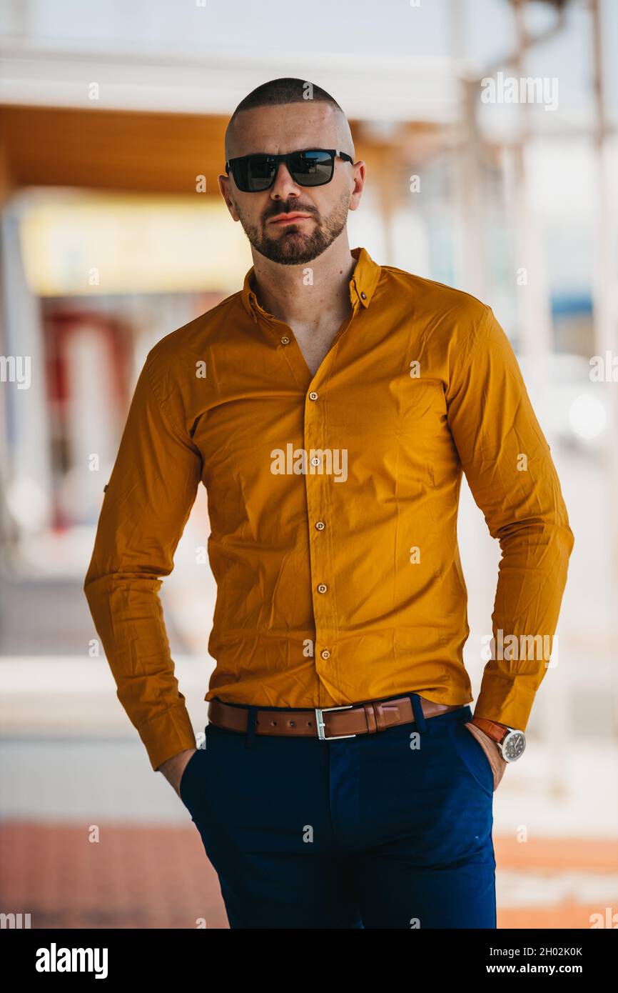 Cool beau homme caucasien portant une élégante chemise de moutarde et des  lunettes de soleil posant à l'extérieur Photo Stock - Alamy