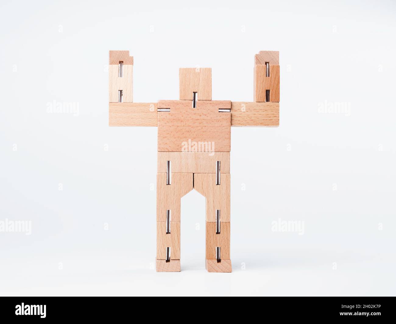 Jouet en bois, robot de bloc géométrique mains vers le haut avec un puissant geste se tenant isolé sur fond blanc, style minimal. Banque D'Images