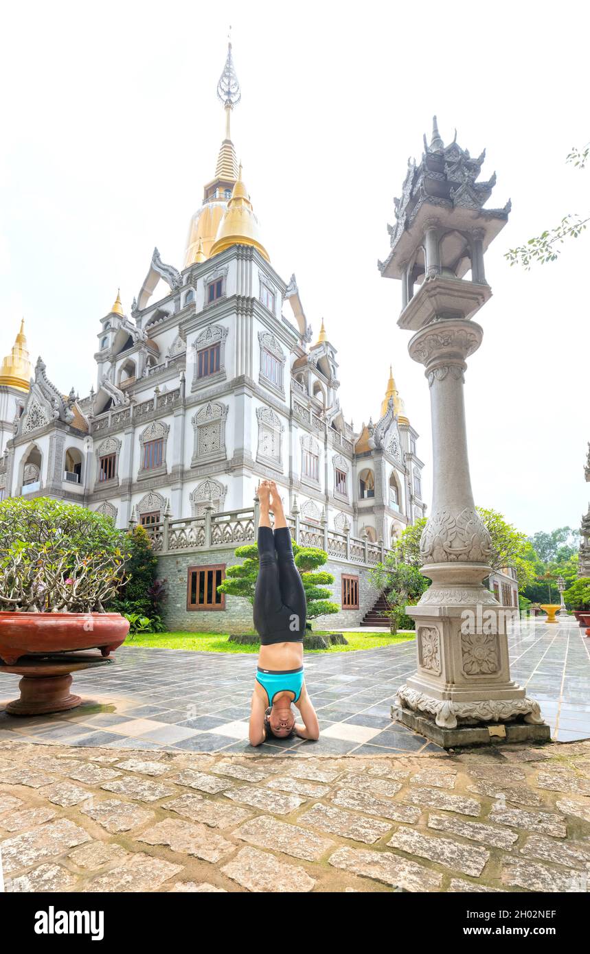 Une jeune femme asiatique s'exerce avec des exercices de yoga difficiles le matin devant la cour du temple pour avoir une bonne santé commencer une journée de travail efficace. Banque D'Images