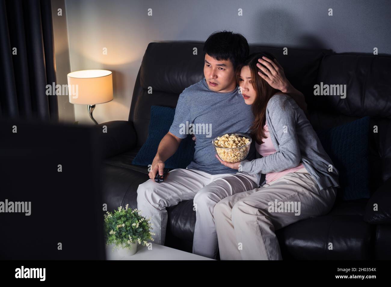 Un jeune couple effrayé regarde un film d'horreur sur un canapé la nuit  Photo Stock - Alamy