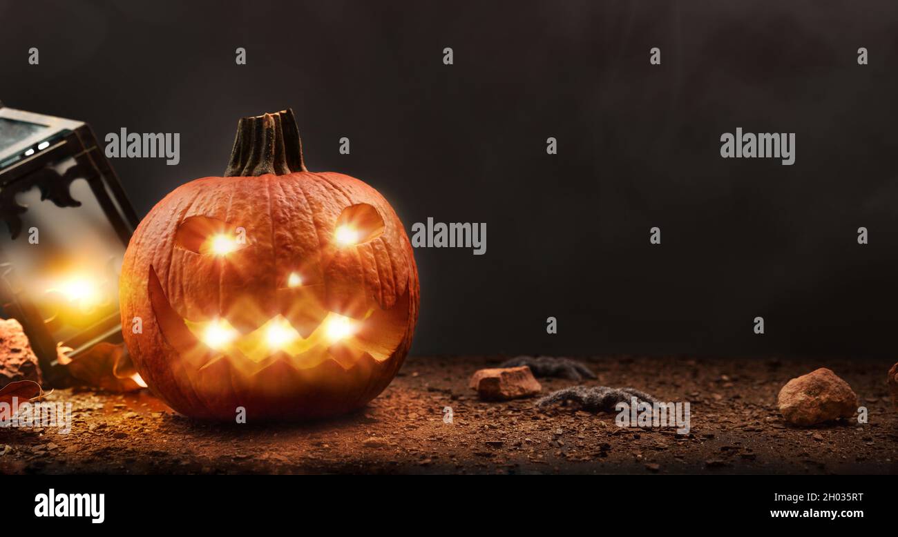 Halloween avec citrouille sculptée et illuminée avec araignées et lanterne isolée sur fond noir.Vue avant.Composition horizontale. Banque D'Images