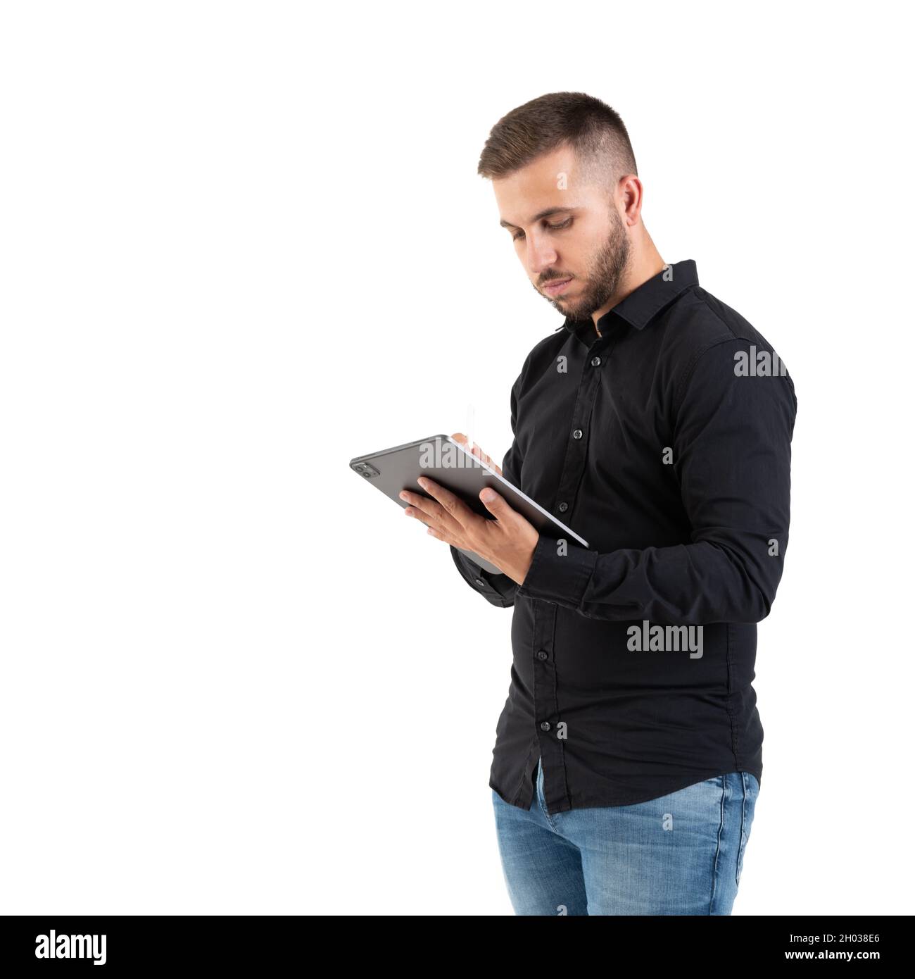 Jeune homme avec une chemise noire regardant une tablette grise sur un fond blanc Banque D'Images