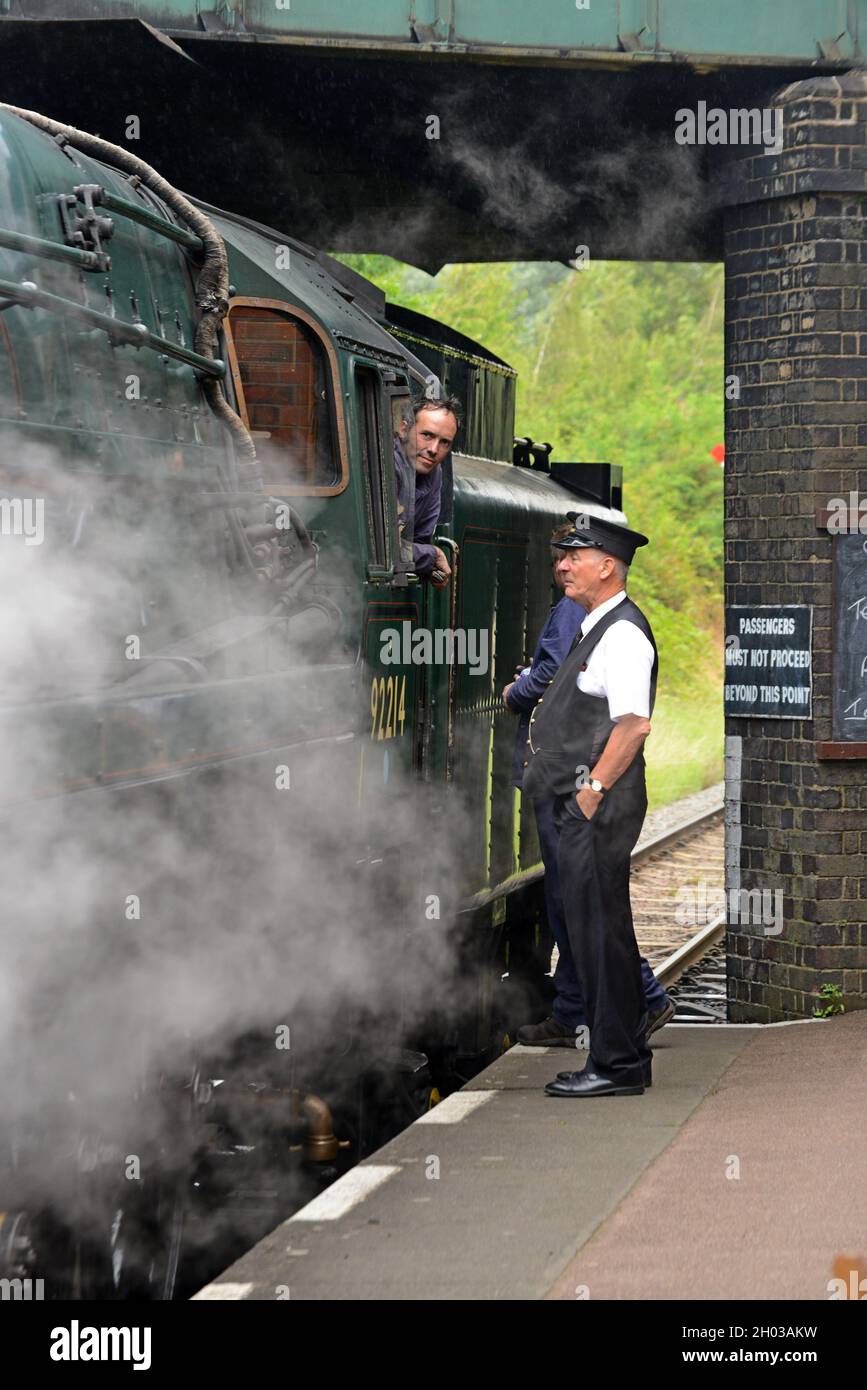Le chauffeur de train de la locomotive à vapeur 9F de l'ex British Railways 92214 discute avec le maître de la gare de Loughborough, Great Central Railway, août 2021 Banque D'Images