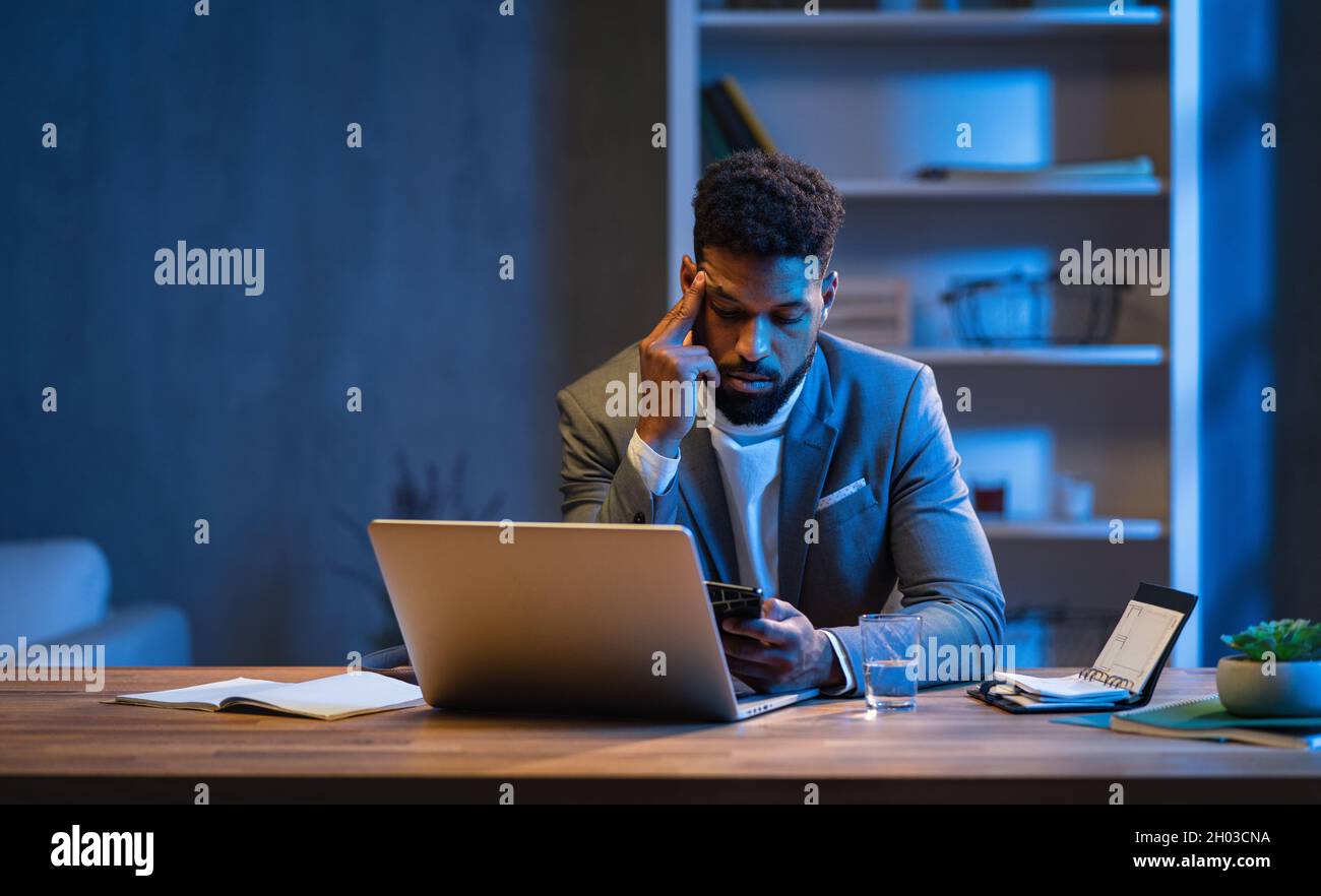 Jeune homme d'affaires afro-américain travaillant à l'intérieur au bureau la nuit. Banque D'Images