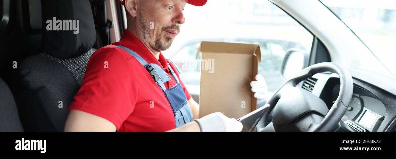 Surprise de la part d'un messager qui a sorti la tablette numérique de sa boîte en carton Banque D'Images Surprise de la part d'un messager qui a sorti la tablette numérique de sa boîte en carton Banque D'Images