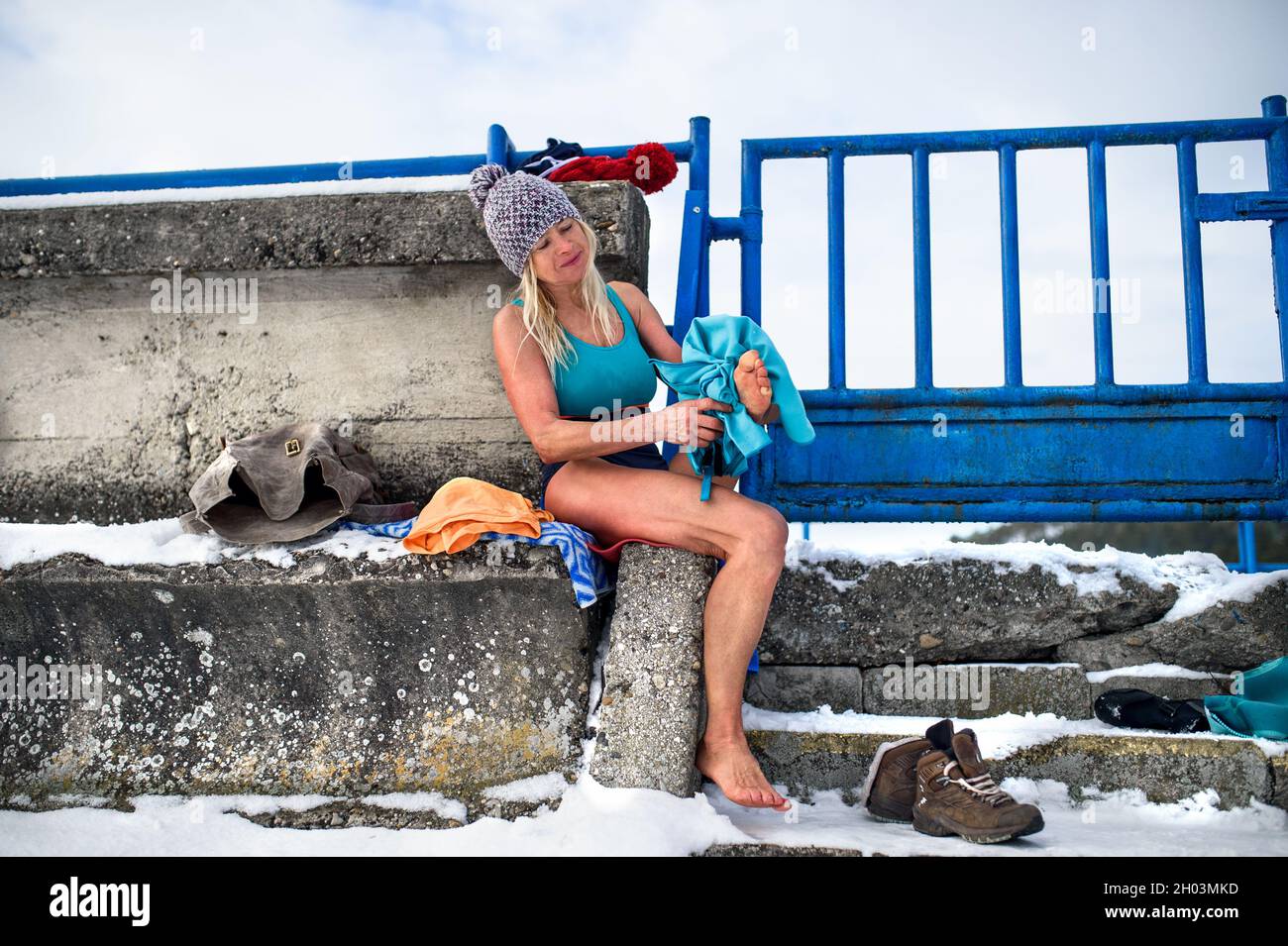 Femme active senior en maillot de bain humide séchage des pieds avec une serviette à l'extérieur en hiver, concept de thérapie froide. Banque D'Images