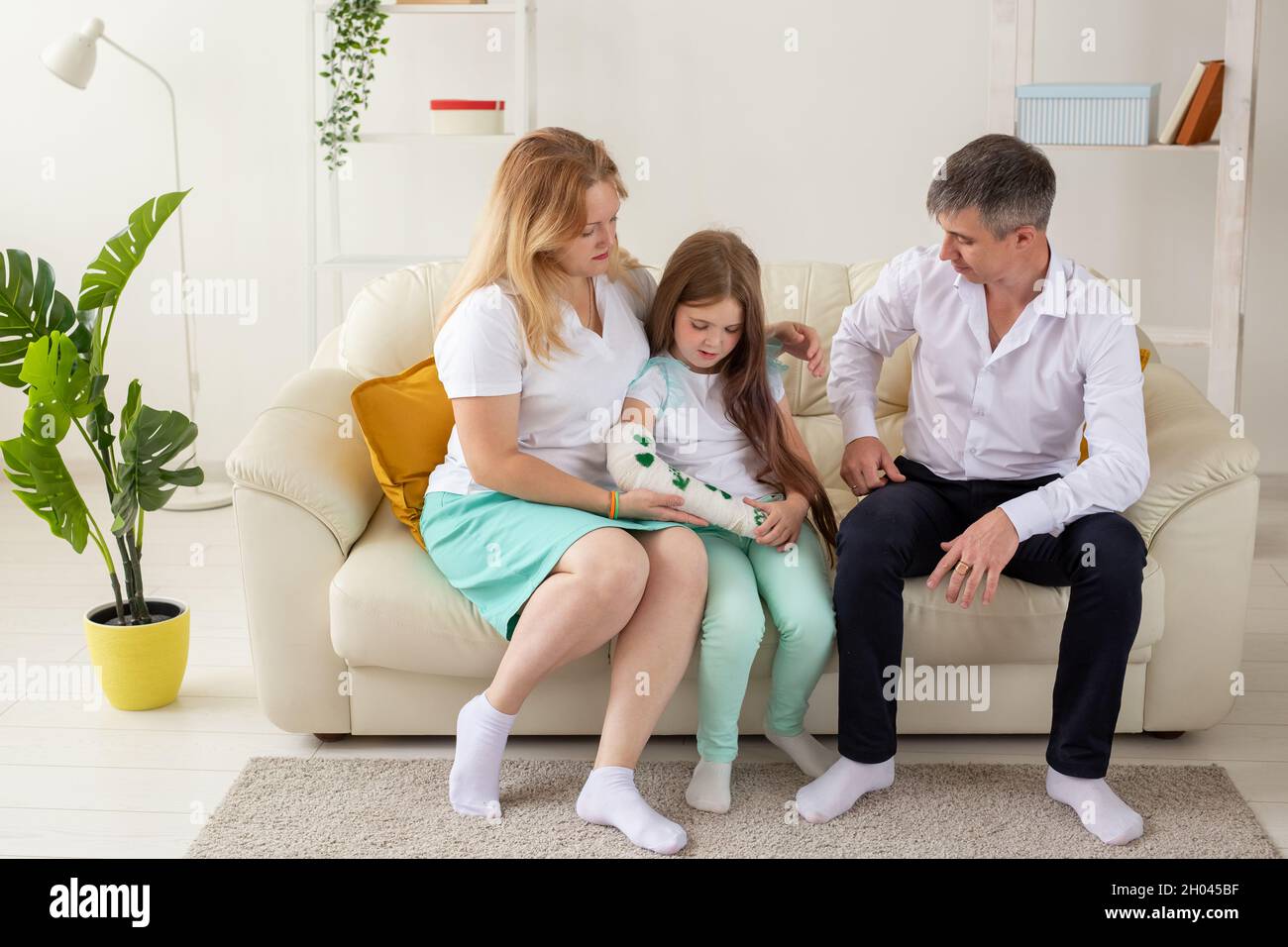 La famille est assise sur un canapé dans leur salon. Fille ont la main  blessée mais elle est heureuse d'être ensemble sa famille Photo Stock -  Alamy