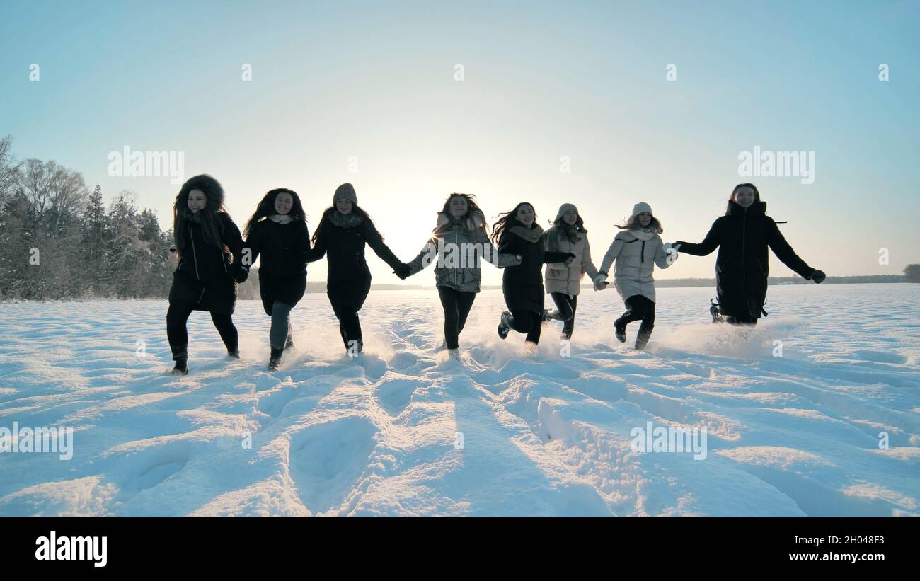 Des filles gaies courent sur le terrain enneigé. Banque D'Images