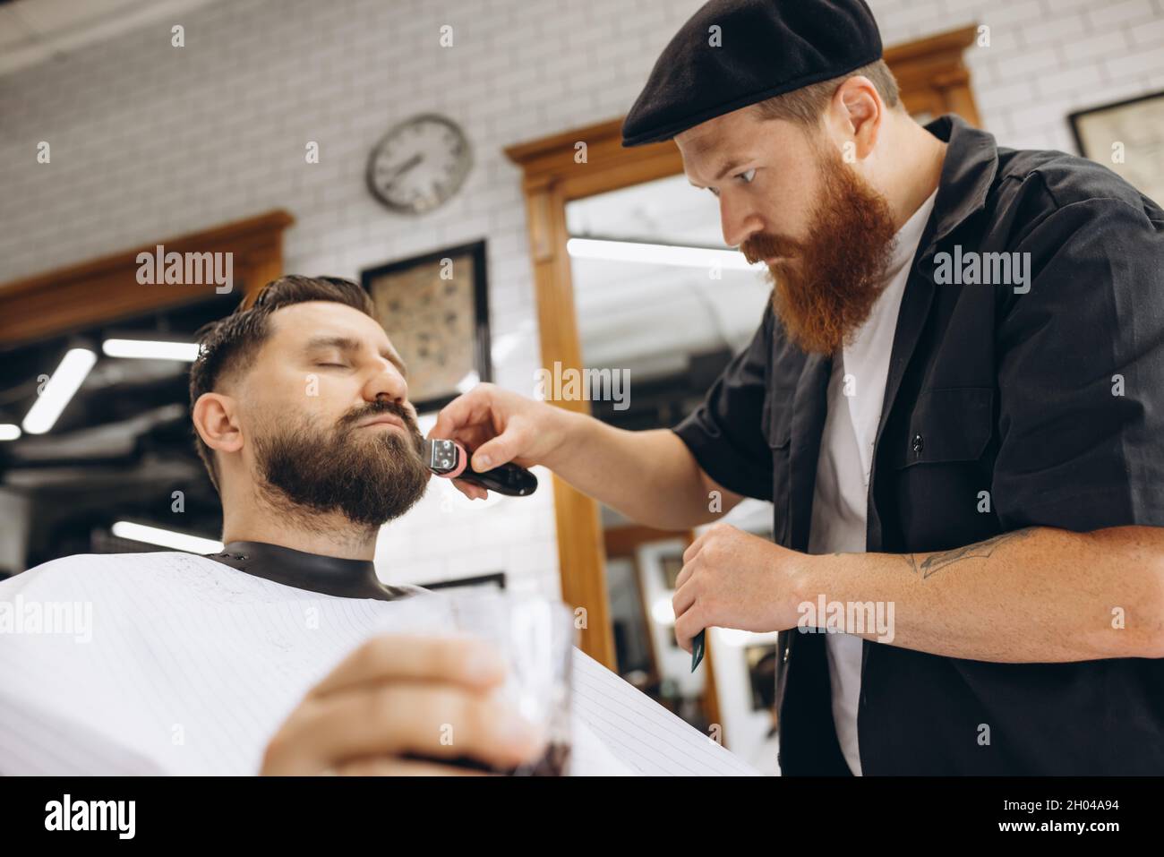 coiffeur professionnel, tondeuse, rasage de la barbe d'un client régulier  dans un salon de coiffure. Beauté, soin de soi, style, mode et concept de  cosmétiques pour hommes Photo Stock - Alamy