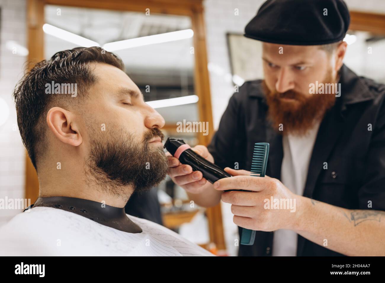 coiffeur professionnel, tondeuse, rasage de la barbe d'un client régulier dans un salon de coiffure. Beauté, soin de soi, style, mode et concept de cosmétiques pour hommes. Banque D'Images