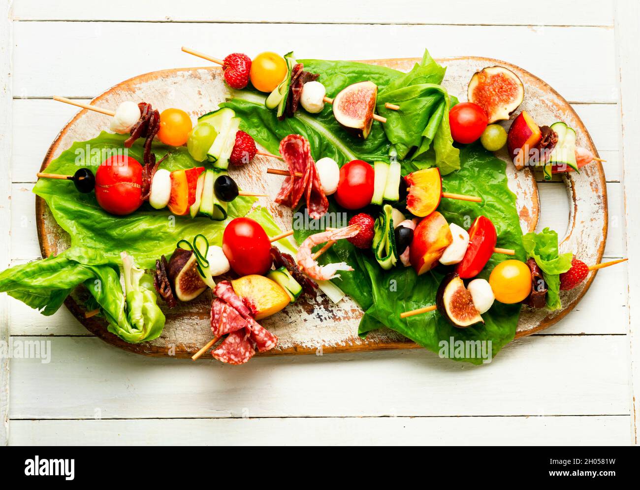 Apéritif de crevettes, jamon, fruits et légumes sur brochettes en bois Banque D'Images