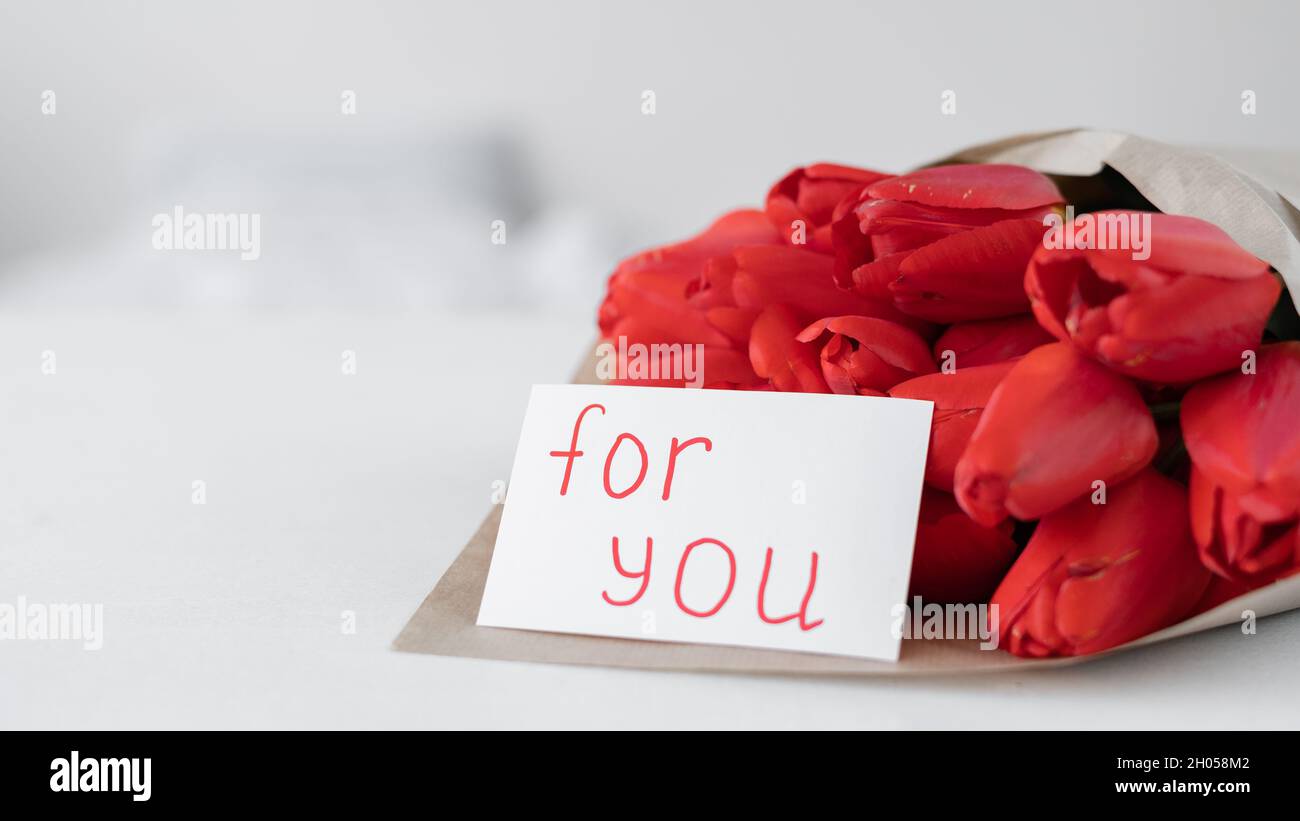 Un bouquet de tulipes rouges et une carte avec inscription pour vous sur fond blanc.Fleurs en papier artisanal.Livraison de fleurs d'anniversaire Banque D'Images