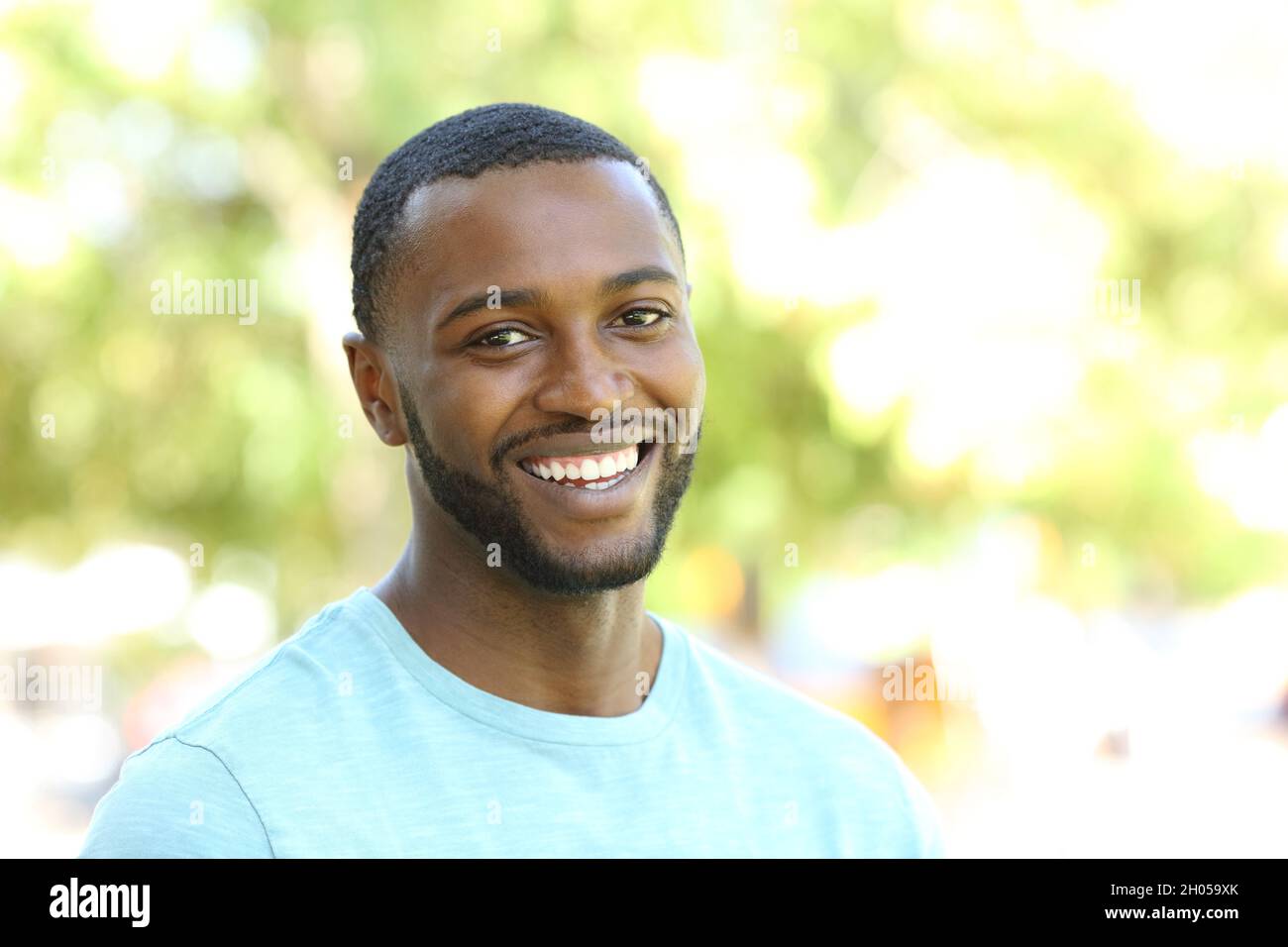 Portrait d'un heureux noir souriant à l'appareil photo dans un parc Banque D'Images