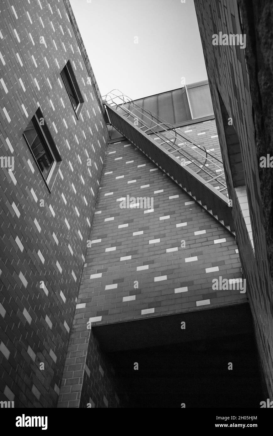 Vue à angle bas sur le bâtiment en brique de la rue latérale avec des escaliers - noir et blanc Banque D'Images