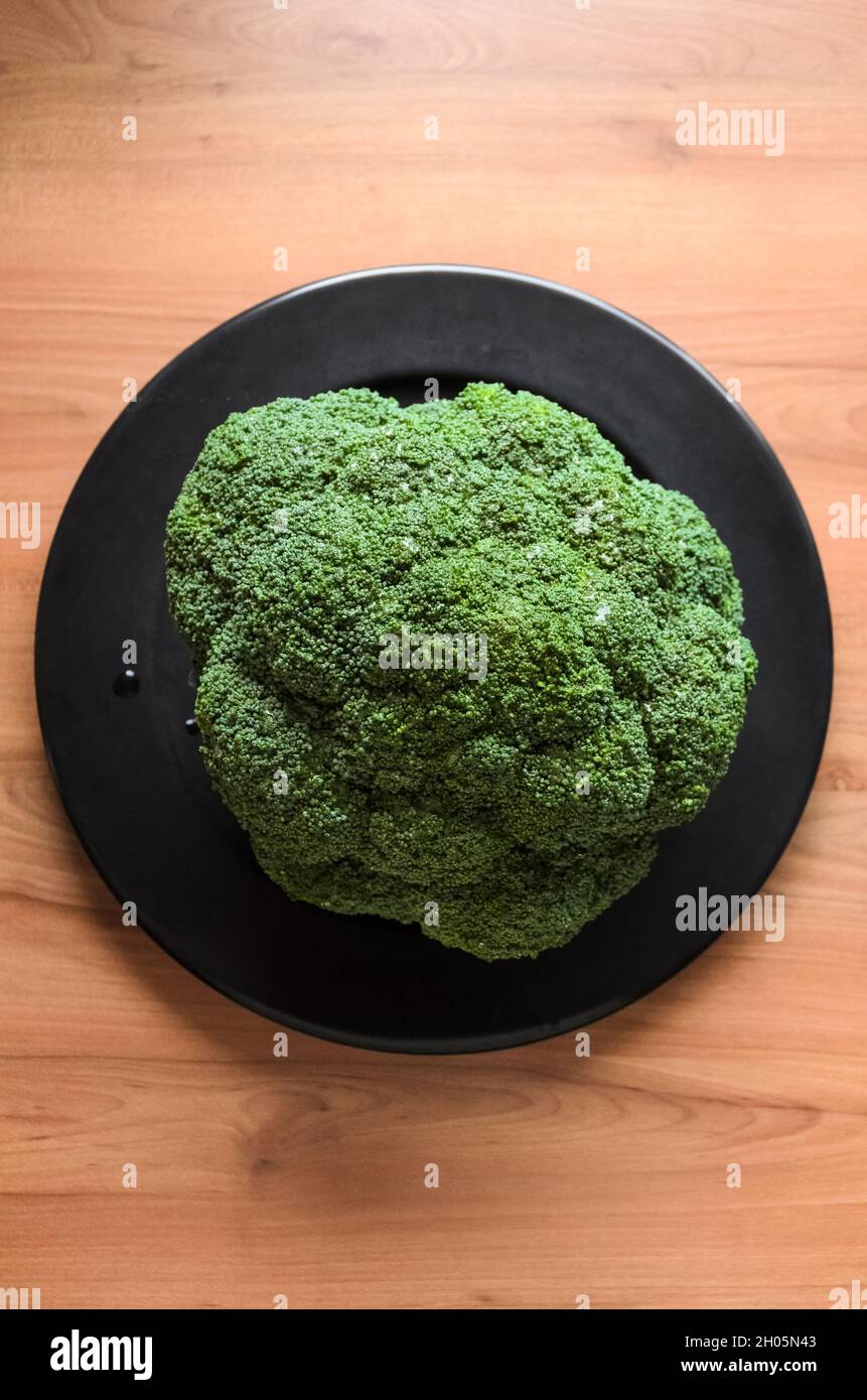 Brocoli (Brassica oleracea) sur une assiette et un bureau en bois dans la cuisine, plan de travail vue de dessus directement Banque D'Images