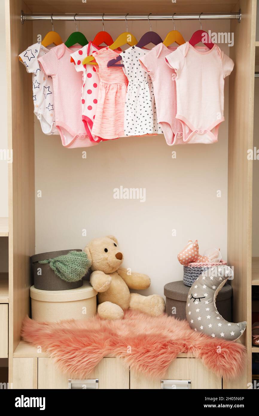 Garde-robe avec de jolis vêtements et jouets pour bébé Photo Stock - Alamy