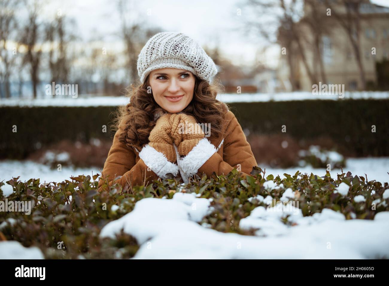 bonne femme moderne avec des moufles dans un bonnet tricoté et un manteau  de peau de mouton dehors dans le parc de la ville en hiver Photo Stock -  Alamy