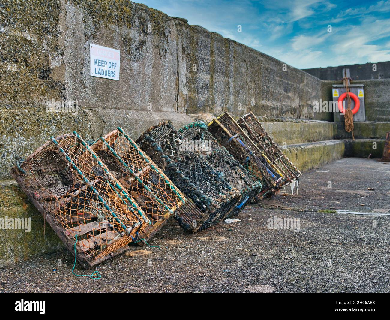 Plusieurs pots de crabe contre le mur de pierre de Craster Harbour à Northumberland, Angleterre, Royaume-Uni Banque D'Images