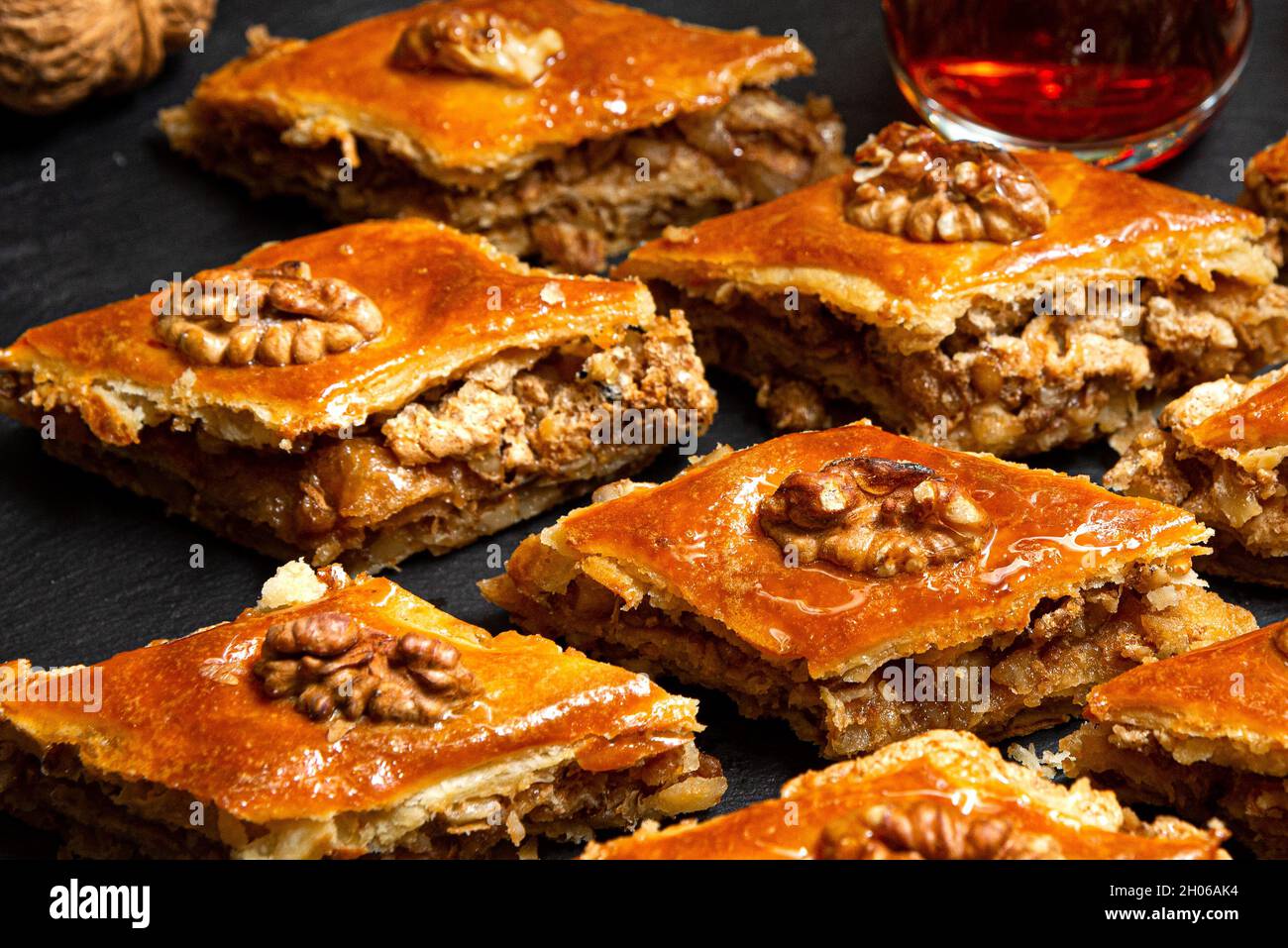 Baklava au miel et noix sur ardoise noire.Portions de sucreries orientales.Morceaux sucrés turcs.Thé versé dans le verre armudu à l'arrière-plan. Banque D'Images