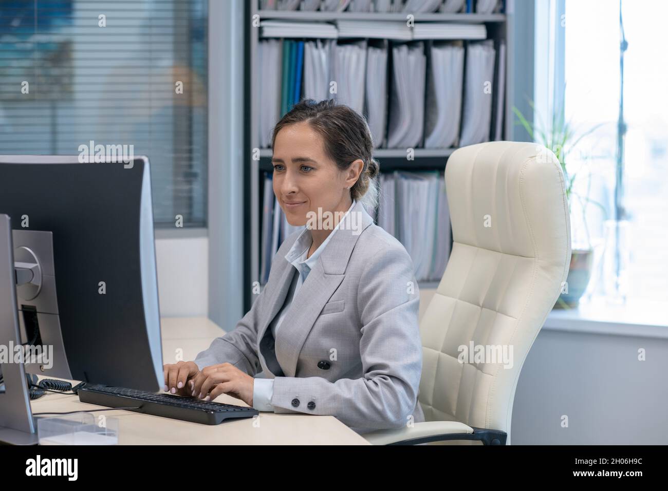 Femme d'affaires contemporaine travaillant devant un ordinateur près de son lieu de travail Banque D'Images