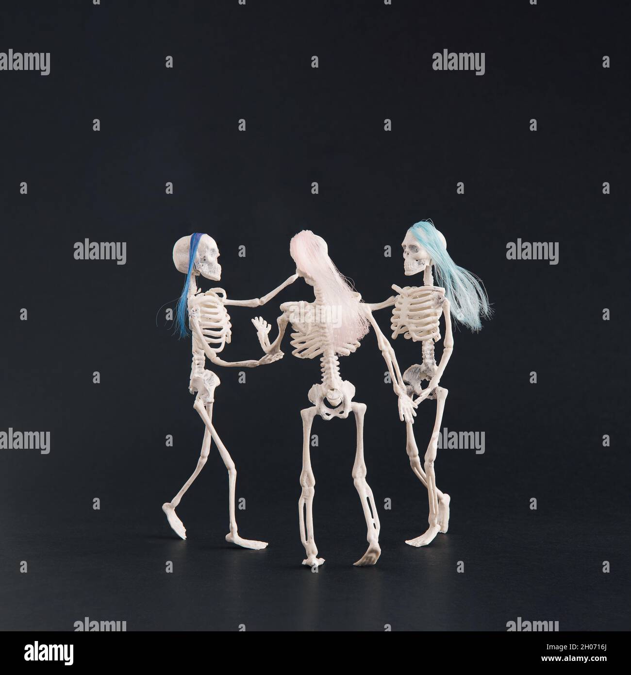 Trois squelettes comme trois grâces dansant sur fond noir.Recadrage carré.Motif Halloween avec espace pour les copies Banque D'Images