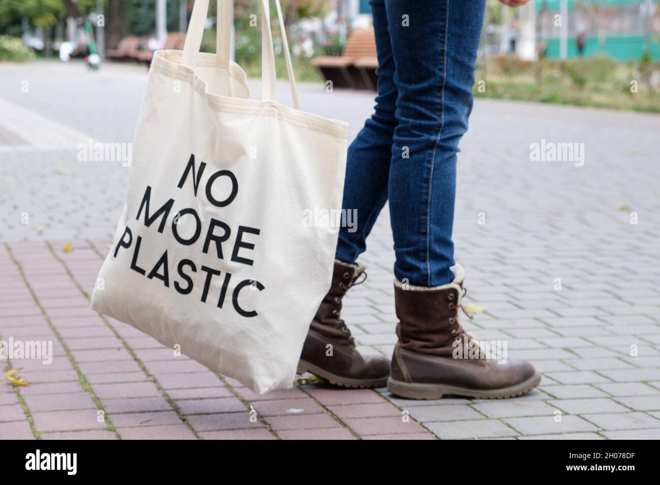 Pieds humains en jeans et bottes avec un sac avec l'inscription plus de plastique Banque D'Images